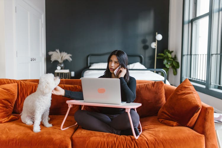 Woman Petting A Dog While On Phone Call