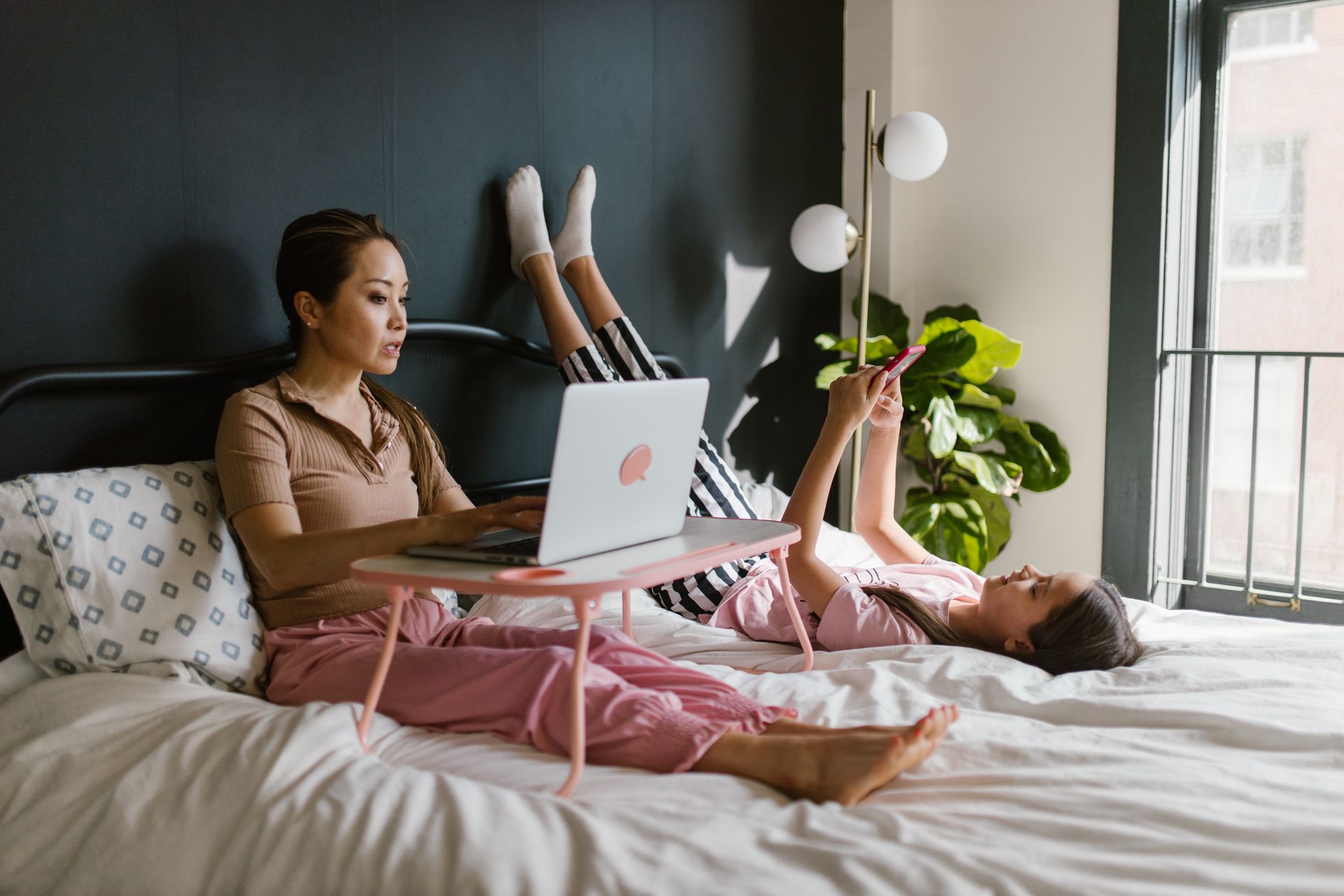 Mother and Daughter Resting on the Bed while Using Gadgets