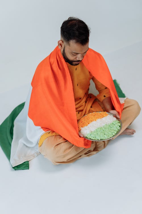 Man Sitting On the Floor with a Flag Covering His Back 