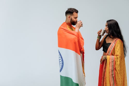 A Man and a Woman Drinking a Glass of Beverage while Looking at Each Other