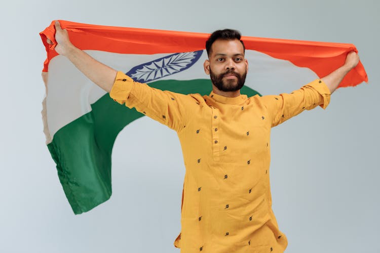 Bearded Man Carrying Indian Flag While Seriously Looking At The Camera