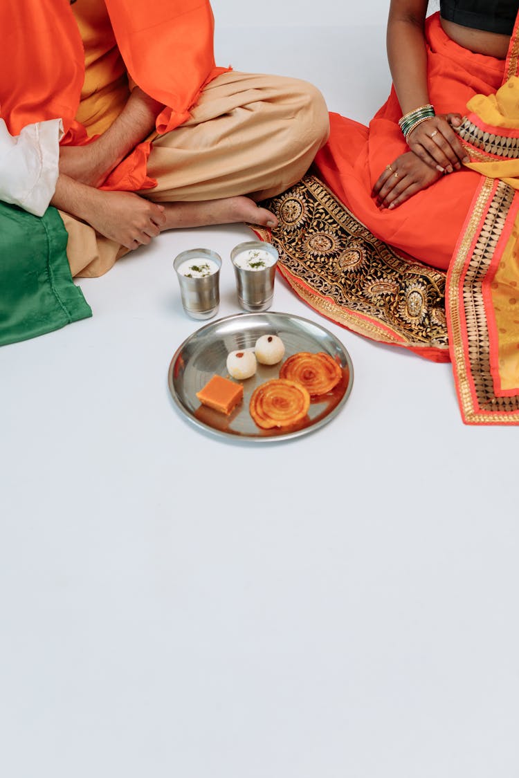 A Man And A Woman Wearing Traditional Clothes Sitting On The Floor