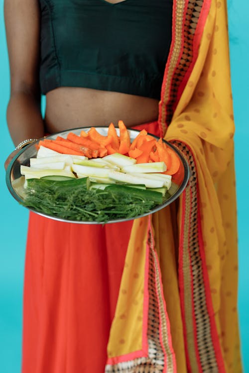 Person Carrying a Stainless Steel Plate with Assorted Vegetable Slices 