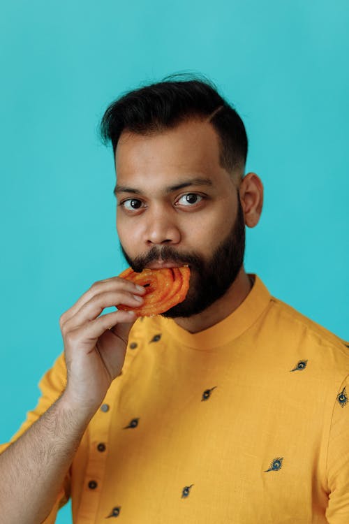 A Bearded Man in Yellow Shirt Eating Food