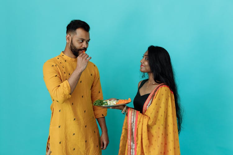 A Couple Wearing Traditional Outfit Eating A Plate Of Vegetables