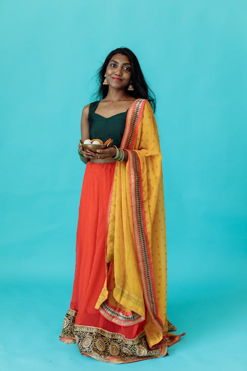 Woman in Traditional Dress Holding a Bowl of Food while Smiling at the Camera