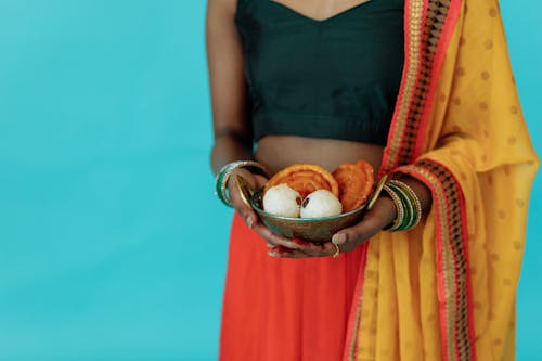 A Woman in Traditional Outfit Holding a Bowl of Traditional Food