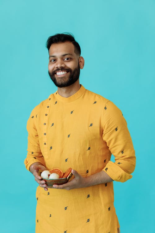 A Man in Yellow Sherwani Holding a Bowl of Food