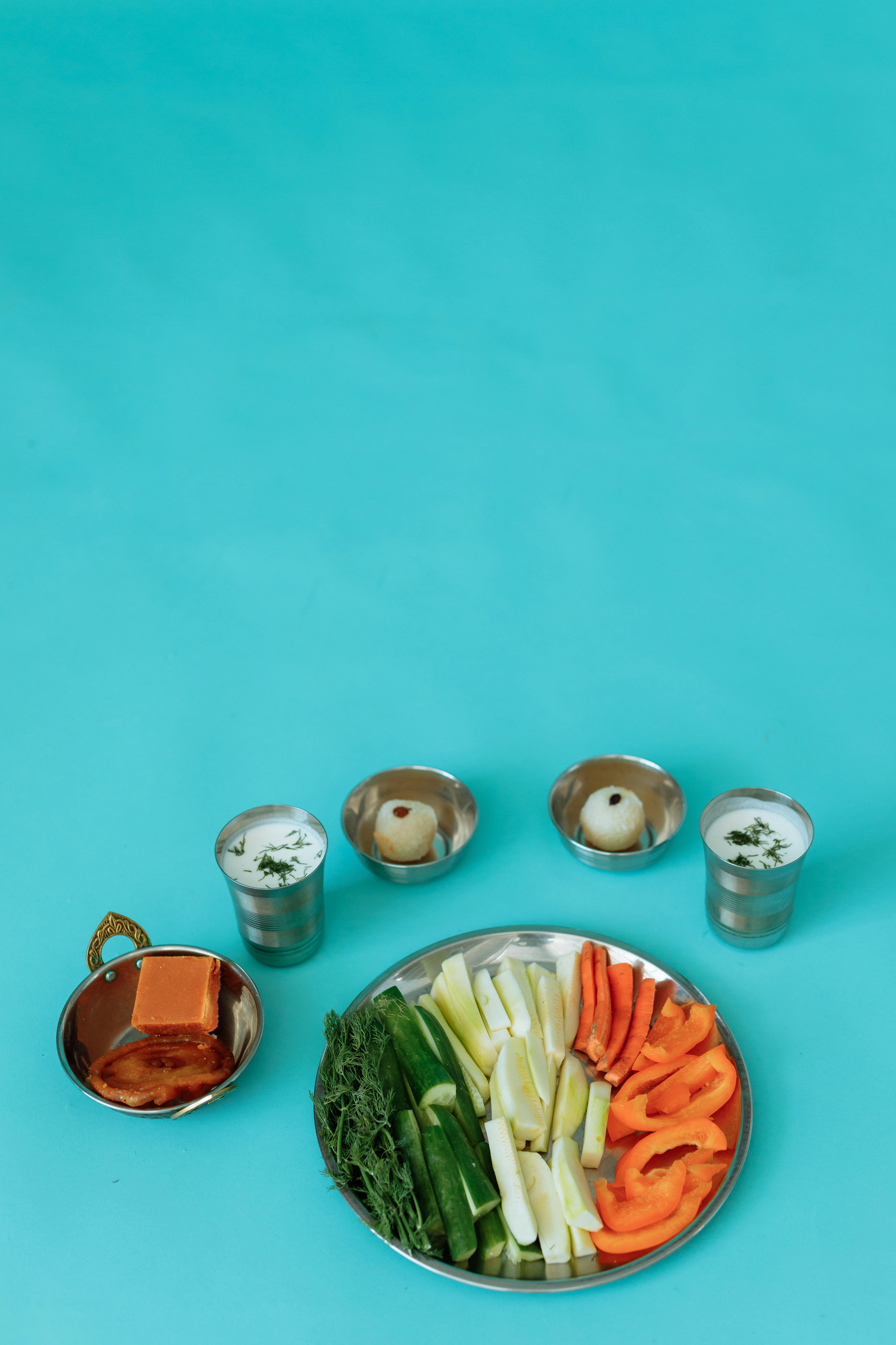 Colorful Indian food display with bowls and drinks on a turquoise backdrop, perfect for cultural celebration themes.