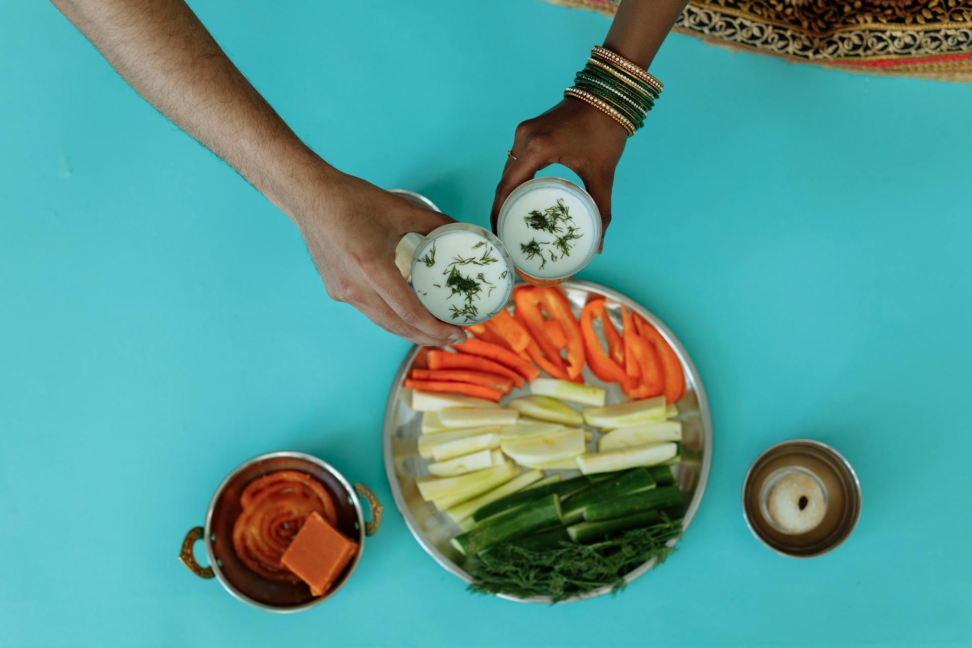 Hands Holding Dip over Plate of Cut up Fresh Vegetables