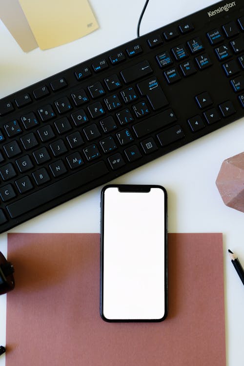 Close-Up Shot of a Mobile Phone beside a Keyboard