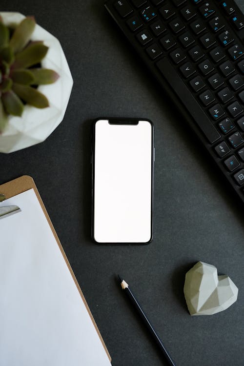Free Close-Up Shot of a Mobile Phone beside a Keyboard and Black Pencil  Stock Photo