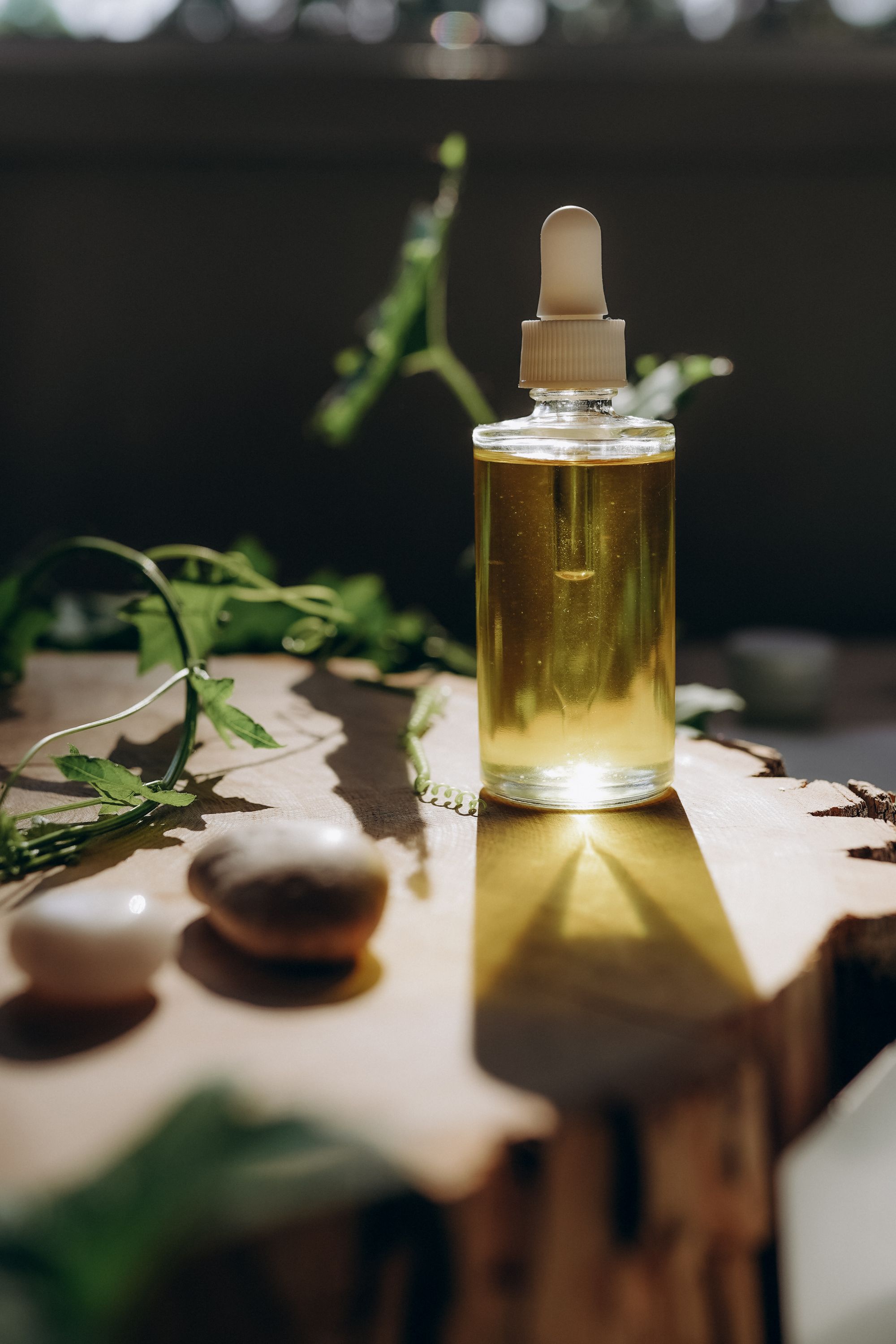 Botanical cold-pressed oil in a glass vessel, set on a warm wooden surface - Ria Naturals craft process