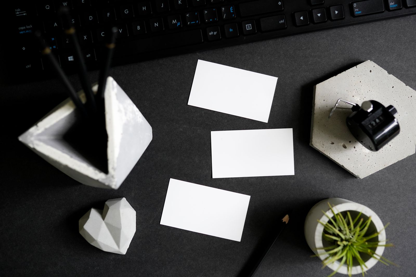 Business cards, keyboard, stationery, and office materials arranged on a dark desk