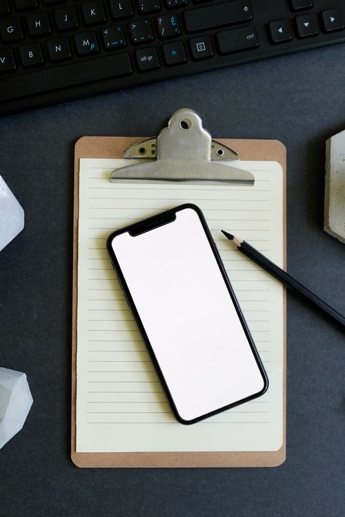 Free Flat lay of smartphone on clipboard with keyboard, perfect for technology and productivity themes. Stock Photo