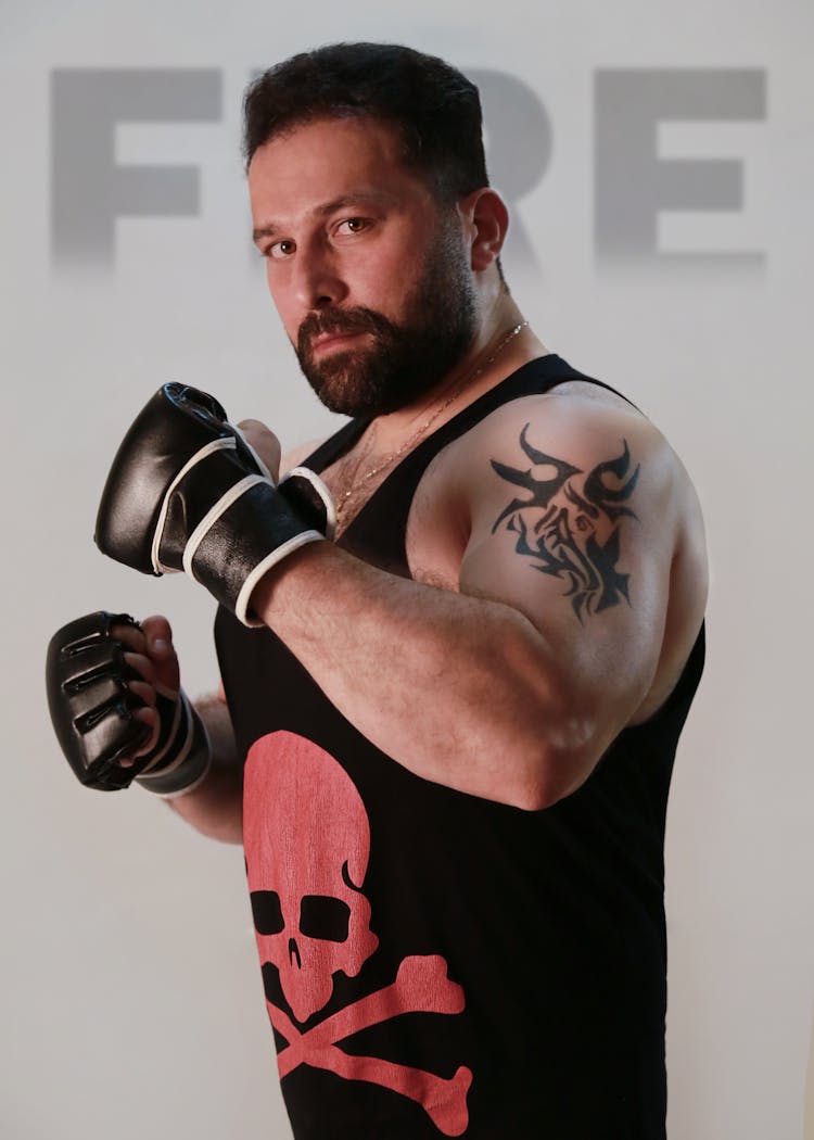 A Man Wearing A Black Tank Top And Kickboxing Gloves