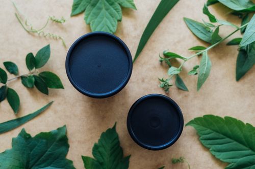 Free Top view of herbal leaves and black containers on a beige background. Stock Photo