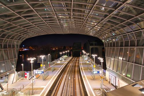 Free A modern train station featuring illuminated platforms under an arched glass roof at nighttime. Stock Photo