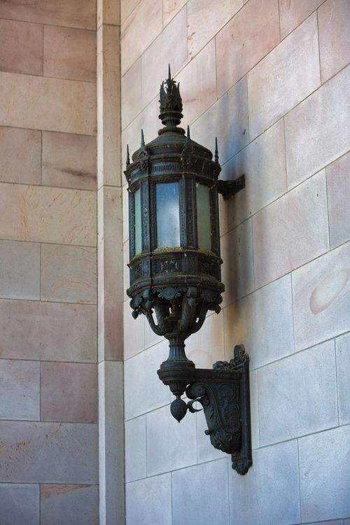 Free Close-up of a vintage metal wall sconce, showcasing intricate design, mounted on a stone wall. Stock Photo