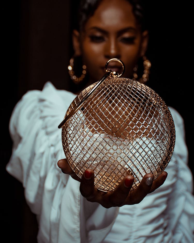 A Woman In A White Dress Holding A Round Metal Object