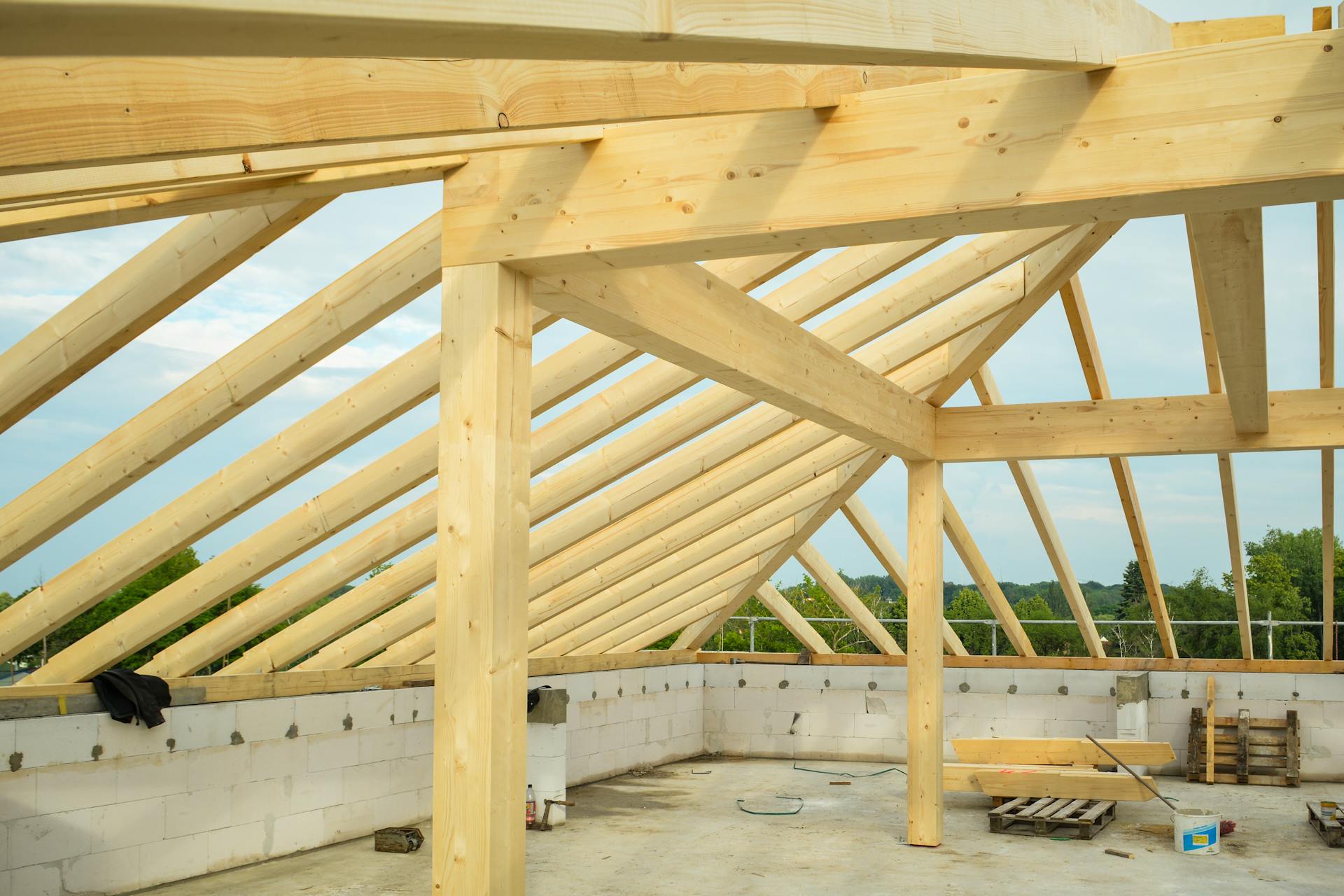 Wooden trusses structure in an unfinished building highlighting construction progress.