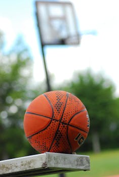 Close-up of a basketball with hoop in the background, highlighting outdoor sports.