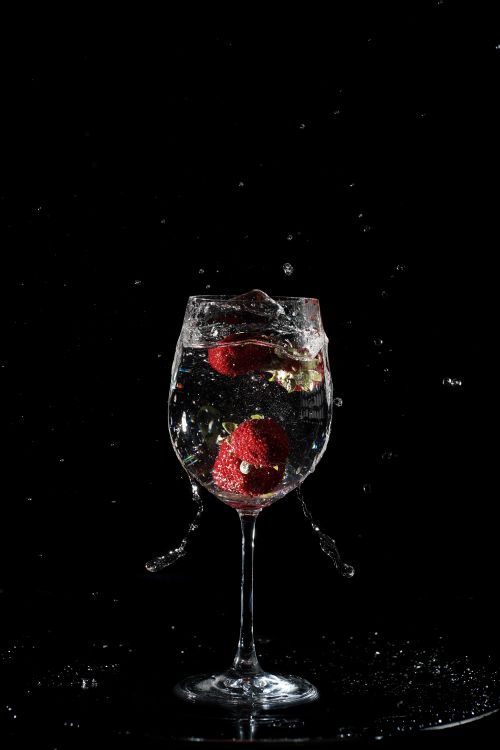 Free Dramatic capture of strawberries splashing in a wine glass against a black background. Stock Photo