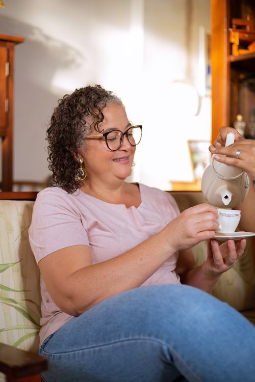 Free Smiling elderly woman with curly hair enjoys a cup of tea indoors. Stock Photo