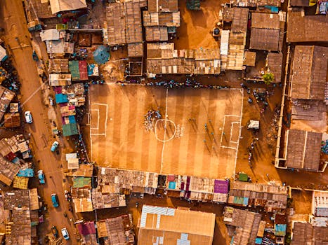 Aerial shot of an urban football field surrounded by dense housing in Accra, Ghana.