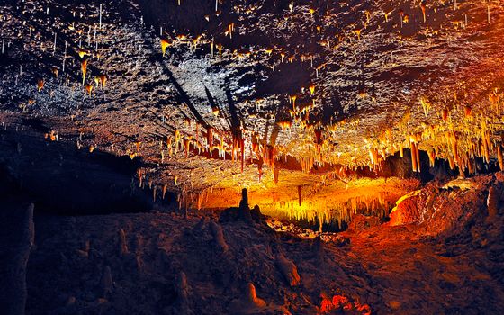 Explore the vibrant colors and unique formations of a stalactite-filled cave, captured in stunning detail.