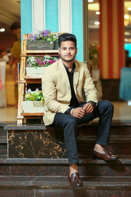 Free Confident man in a beige blazer sitting on stairs indoors, showcasing fashion style. Stock Photo