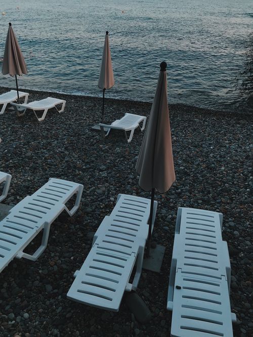 Free Tranquil beach with sunloungers and umbrellas on a pebble shore by the ocean. Stock Photo