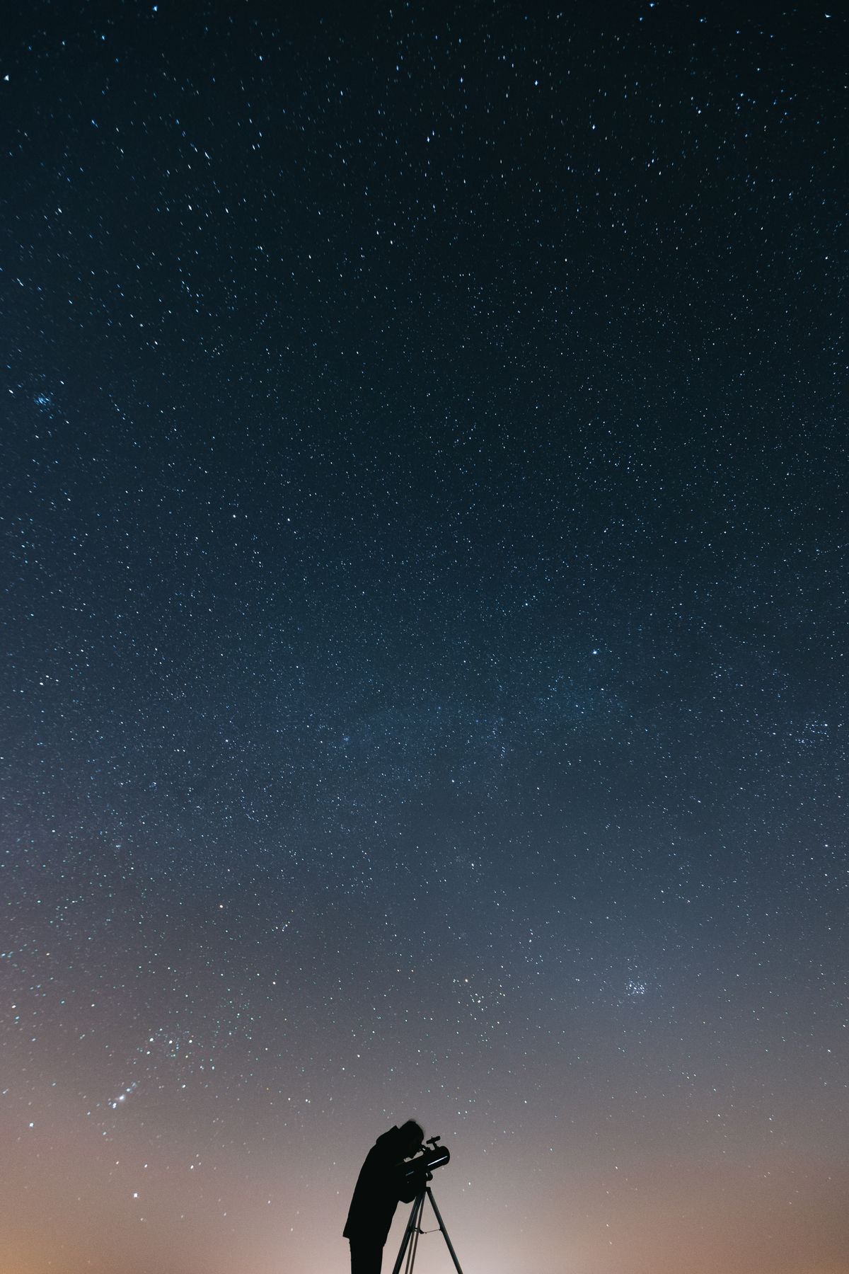 astronomer using a telescope under stars