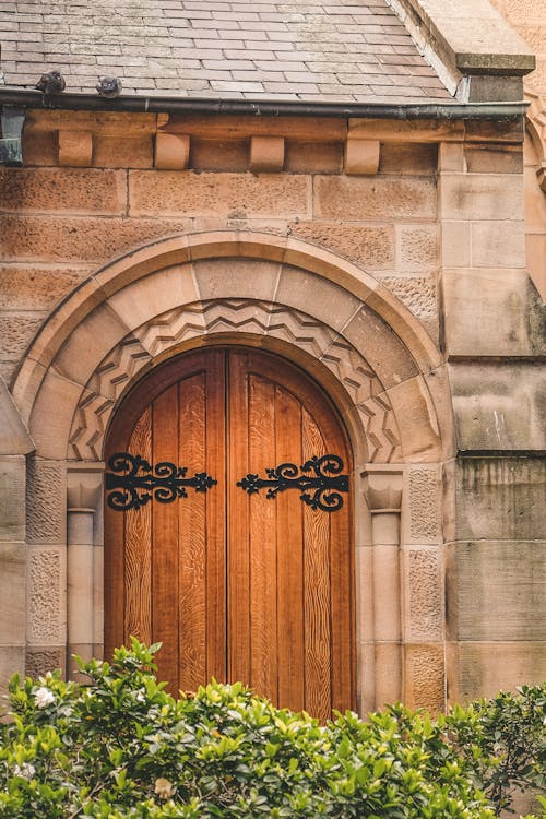 Vintage Wooden Door in Stone Building Behind Bush