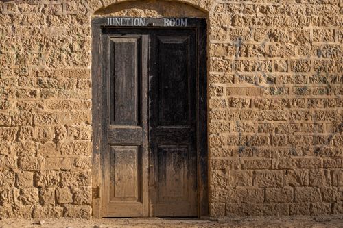 Free A vintage wooden door on a weathered brick wall with 'Junction Room' sign above. Stock Photo