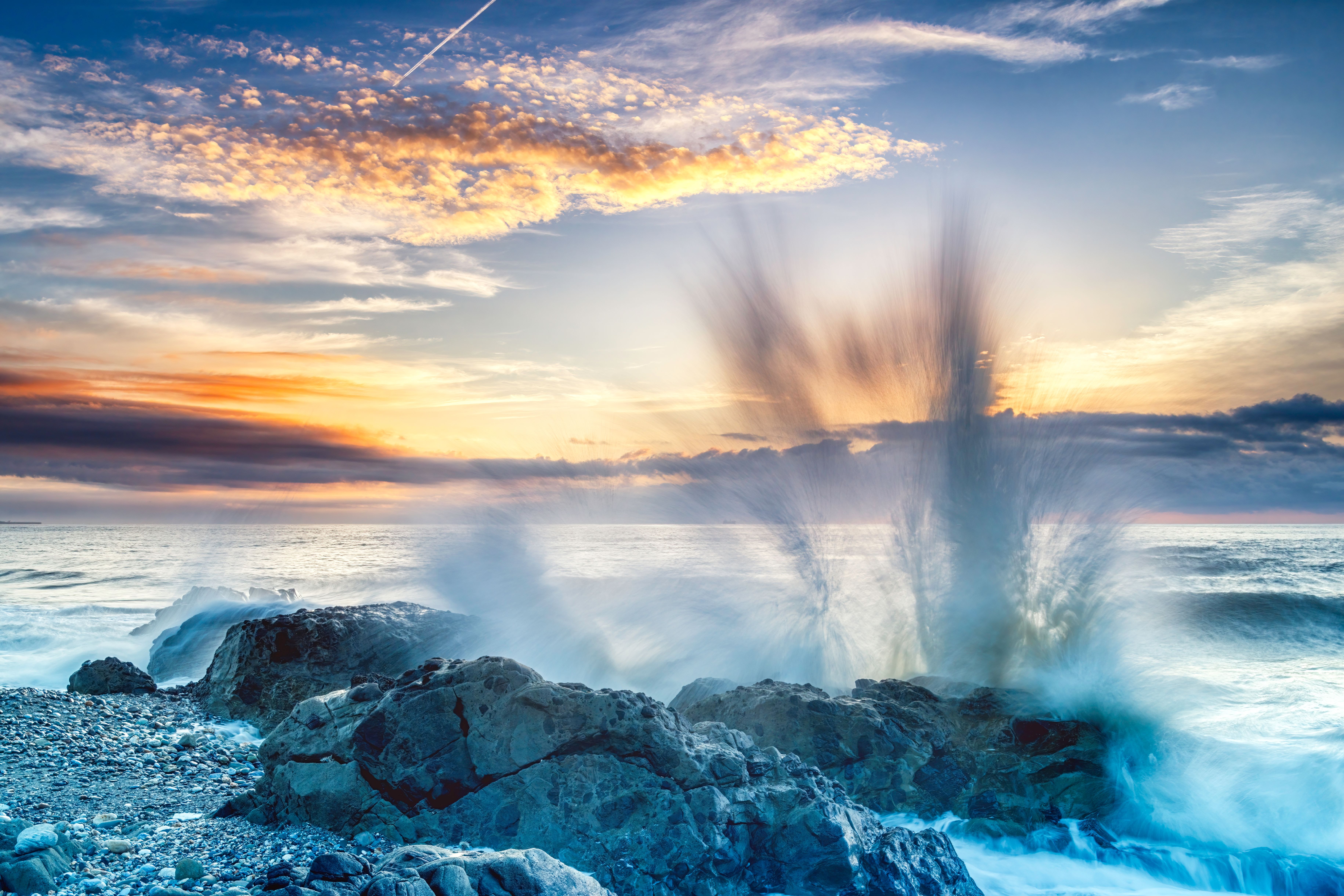 Captivating sunset scene in Taiwan with waves crashing on rocky beach, highlighting nature's power and beauty.