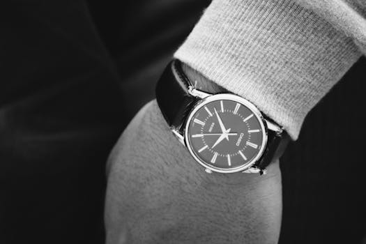 Elegant black and white photograph featuring a wristwatch on a person's hand, emphasizing fashion and time.