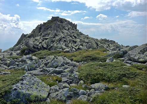 Stunning view of a rocky mountain peak with lush greenery on a clear day.