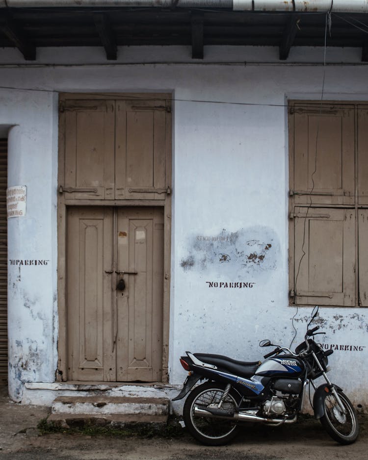 Black Motorcycle Parked Beside Wall With No Parking Sign