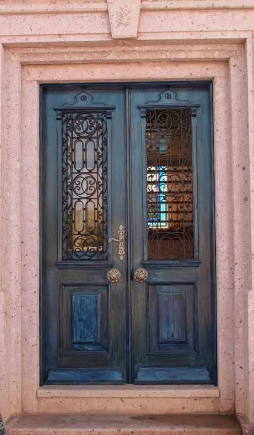 Free A classic wooden door with intricate glass and ironwork set in a vintage facade. Stock Photo