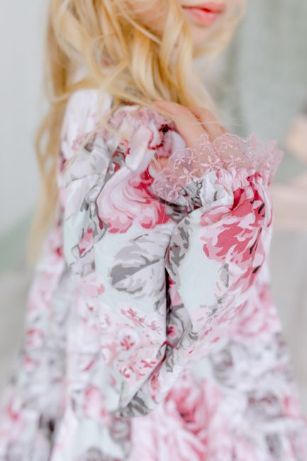 Close-up of a blonde woman in a floral dress posing elegantly, emphasizing texture and pattern.