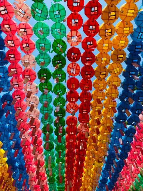 Free Vivid multicolored lanterns hanging under a bright blue sky, creating a festive atmosphere. Stock Photo