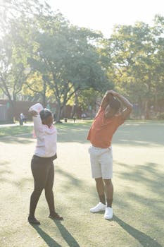 Two adults stretching in a sunny park, embodying a healthy lifestyle and wellness.