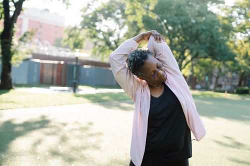 Free African American woman in a park doing stretching exercises on a sunny day. Stock Photo