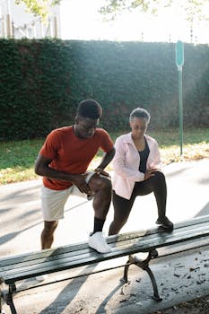 A black couple performing outdoor exercises on a park bench, promoting fitness and a healthy lifestyle.