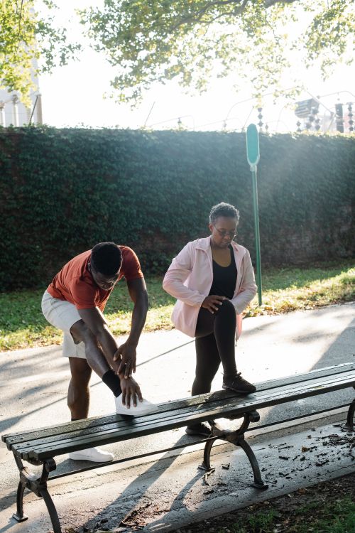 Free African American couple stretching together on a park bench during a sunny day workout. Stock Photo