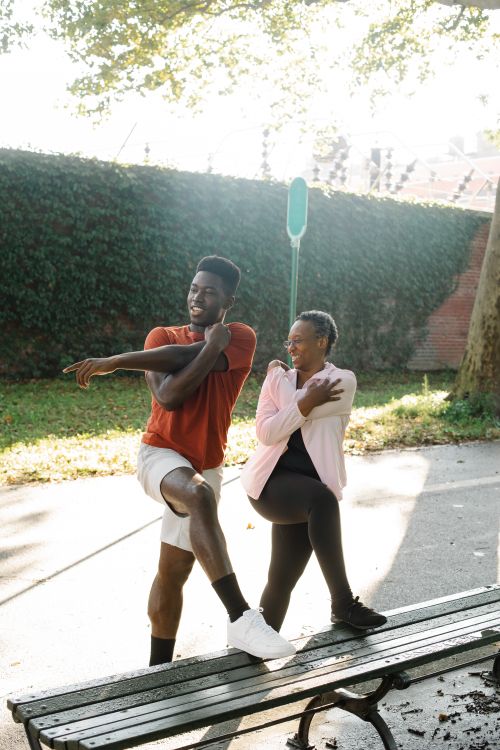 Free Two adults stretching in a sunny park, fostering fitness and wellness. Stock Photo