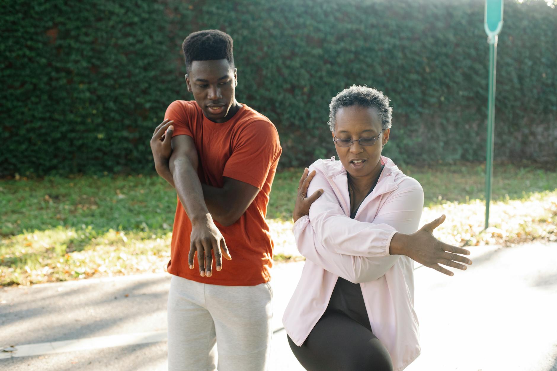Two people stretching outdoors, promoting a healthy lifestyle.