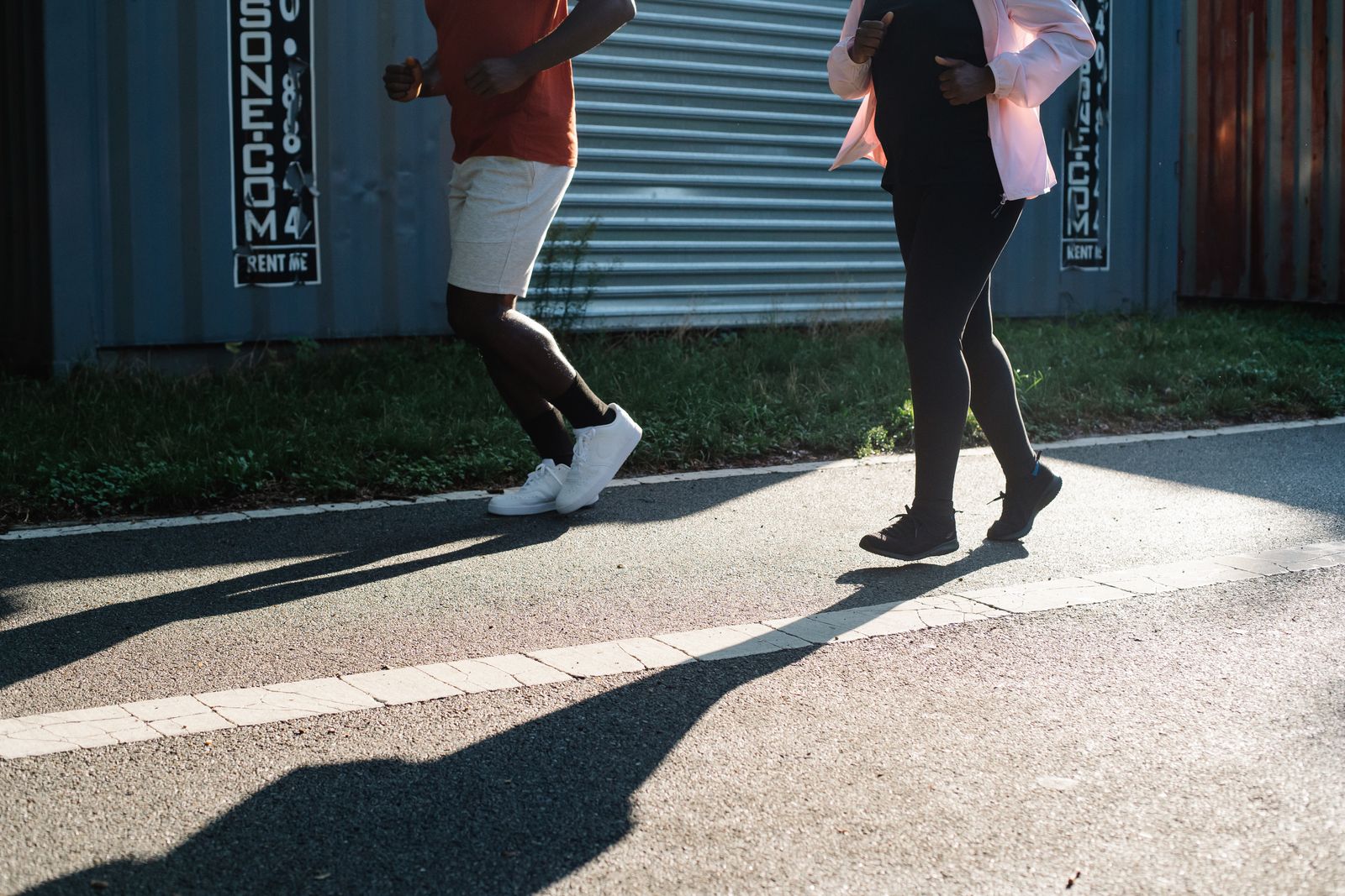 Two people running on a sidewalk