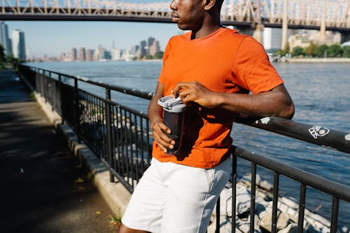 Foto d'estoc gratuïta de afroamericà, barana, camisa ataronjada